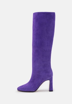 Botte haute en daim violet avec bout pointu et talon bloc, vue de côté sur fond blanc.