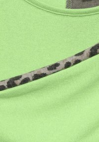 Ljusgrön stickad tyg med en diagonalt mönstrad rand av mjukt, gråaktigt tyg med ett svart leopardmönster.