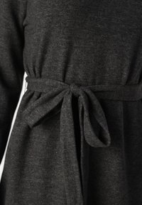 Γκρίζα, μαλακή φόρεμα από ύφασμα με ζωνάκι που δένει στη μέση, με μακριά μανίκια και άνετη γραμμή, κατάλληλο για καθημερινές εμφανίσεις.