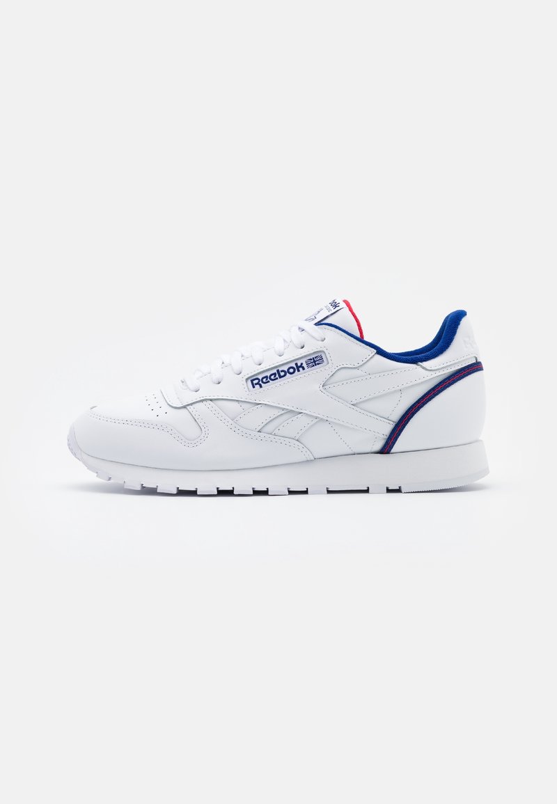 White Reebok leather sneaker with blue and red accents, side logo, white laces, and a textured sole on a plain white background.