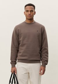 Sweat-shirt marron en matière douce avec un col rond et des poignets côtelés. Présente un petit logo noir "II" à l'avant.