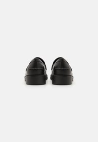 Black leather shoes with a smooth finish, rounded edges, and a low, textured rubber sole, featuring stitching accents at the heel.