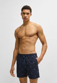 Navy swim shorts with a drawstring waist, featuring a subtle pattern of light blue motifs, crafted from lightweight fabric.