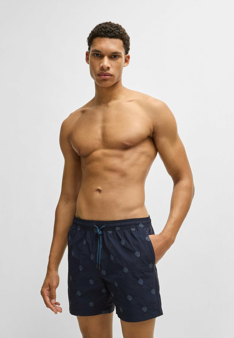 Navy swim shorts with a drawstring waist, featuring a subtle pattern of light blue motifs, crafted from lightweight fabric.