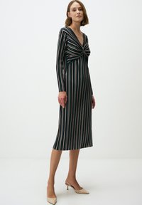 Langes gestreiftes Kleid mit tiefem V-Ausschnitt, gedrehtem Oberteil und voluminösen Ärmeln. Die Farben umfassen Dunkelgrün, Rosa und Creme. Weicher Stoff und knielang.