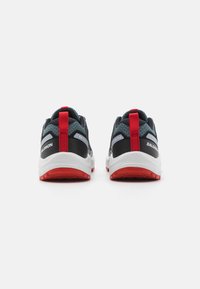 Scarpe sportive con una tomaia in mesh nera, accenti rossi e una suola bianca. Nota linguetta posteriore e suola con grip testurizzato.