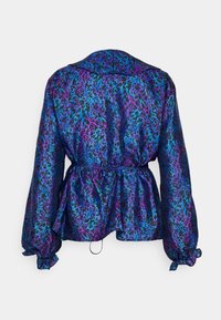 Tylny widok na żywą, wielokolorową bluzkę z niebiesko-fioletowym wzorem panterki, ściągniętą w talii z bufiastymi rękawami.