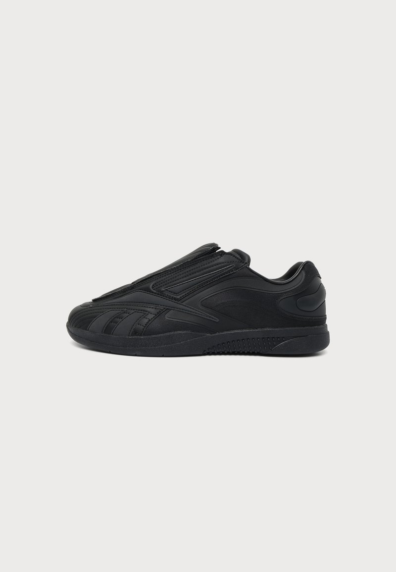 Μαύρο sneaker χαμηλού ύψους με λείες και υφασμάτινες επιφάνειες, στρογγυλεμένη μύτη και λαστιχένια σόλα, εμφανίζεται από το πλάι σε λευκό φόντο.