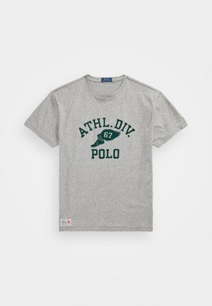 Grå T-skjorte med korte ermer og rund hals, med grønn trykt tekst "ATHL. DIV. 67 POLO" og et logo-patch på den nederste kanten.