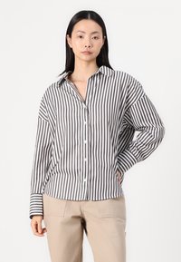 Striped button-up shirt in white and dark gray, with a relaxed fit, pointed collar, and long sleeves. Fabric appears smooth and lightweight.