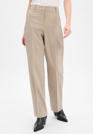 Beige, maßgeschneiderte Hose mit geradem Schnitt. Mit Falten und einer glatten Textur, kombiniert mit schwarzen spitzen Ankle Boots.