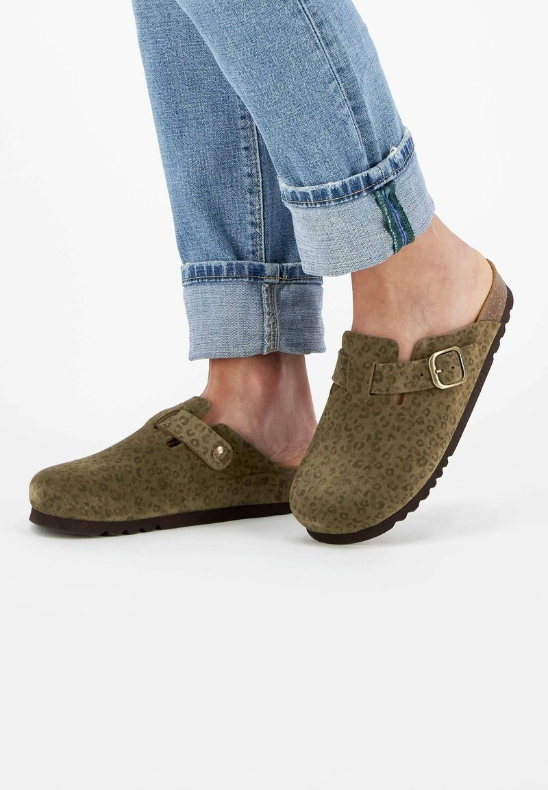 Grüne Wildlederclogs mit einem Leopardenmuster, ausgestattet mit einem Knöchelriemen, einer runden Zehe und einer strukturierten Gummisohle. Oben umgeschlagene Denim-Cuffs.