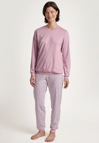 Maglietta a maniche lunghe rosa chiaro abbinata a pantaloni del pigiama con motivi a fiori piccoli. Tessuto morbido, polsini elastici sui pantaloni.