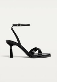 Schwarze Sandaletten mit Absatz und schlankem Design, ausgestattet mit einer quadratischen Spitze, mehreren überkreuzten Riemen und einem Knöchelriemen mit Schnalle.