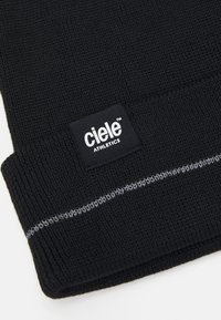 Black knit beanie with a folded cuff, featuring a stitched gray accent and a rectangular black tag with white text, "ciele ATHLETICS."
