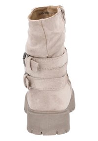 Bottine en daim beige clair avec deux accents de sangle réglables et une semelle en caoutchouc texturé, présentant un bout rond et un design décontracté.