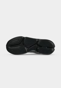 Semelle de chaussure noire avec motif de bande de roulement courbé et segmenté conçu pour l'adhérence et la flexibilité, présenté sur fond blanc uni.