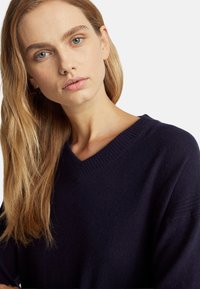 Jersey de cuello en V navy de suave tejido de punto, con un cuello acanalado y un corte relajado, con una textura sutil y un diseño ligero.