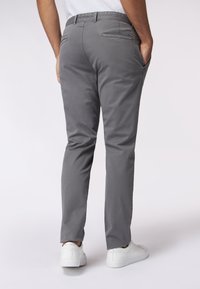 Chino grigi con un taglio slim e una texture liscia, dotati di tasche posteriori e una cintura, abbinati a sneaker bianche.