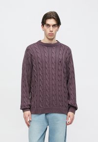 Πουλόβερ σε μωβ χρώμα με πλέξη καλωδίου, στρογγυλή λαιμόκοψη και μακριά μανίκια. Διακριτό ανάγλυφο σχέδιο σε όλο το ύφασμα με ριμπ μανσέτες και τελείωμα.