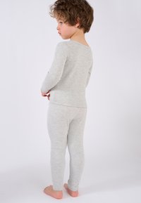 Maglia a maniche lunghe grigia con leggings coordinati, realizzati in un tessuto morbido, caratterizzati da un design aderente e una superficie liscia, con un discreto motivo mélange.