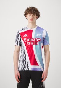 Maillot à manches courtes Adidas présentant un dégradé de sections rouge, bleu et blanc, avec des motifs abstraits noirs et le texte "Emirates Fly Better".