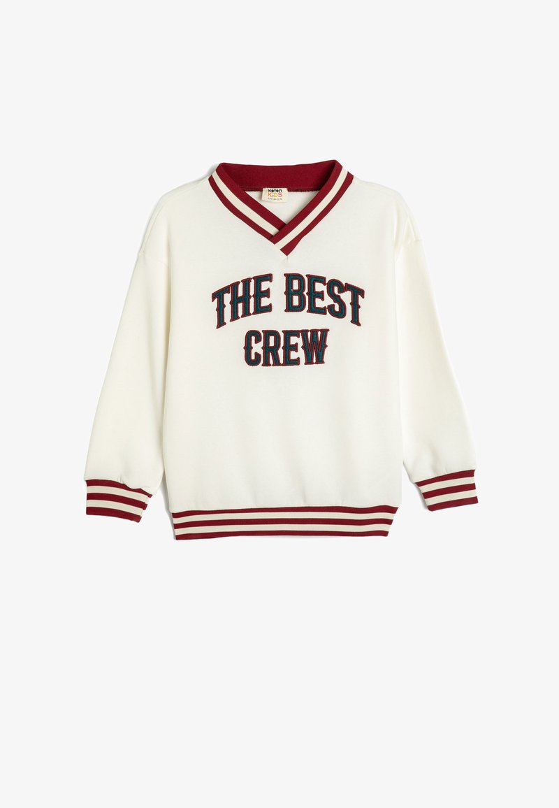 Suéter blanco con escote en V, que presenta el texto bordado en rojo y azul "THE BEST CREW". Puños y dobladillo de canalé a rayas rojas. Textura suave.