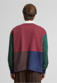 Farvet blokeret langærmet skjorte med maroon, grøn, brun og navy sektioner. Blødt stof med en afslappet pasform og ribbede manchetter.