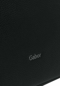Borsa in pelle nera texturizzata con un piccolo logo "Gabor" in argento. La superficie presenta una finitura a granuli, che aggiunge un elemento tattile.