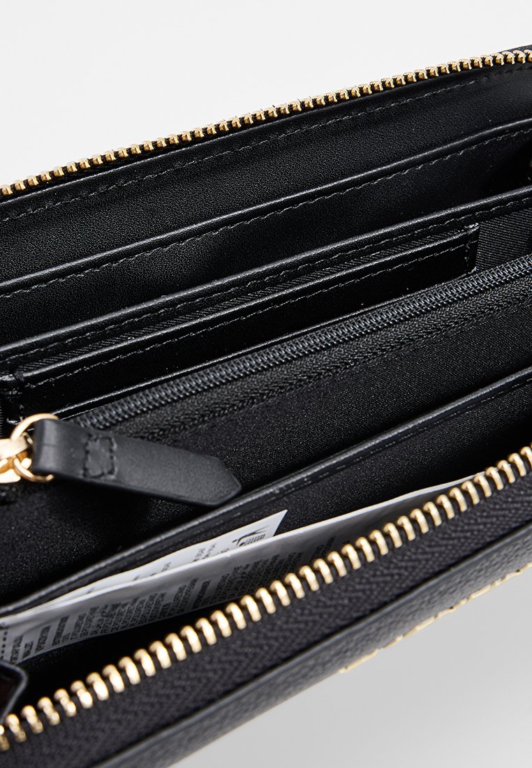 Portefeuille noir avec fermeture éclair dorée, doté de plusieurs emplacements pour cartes, d'un compartiment zippé et d'un matériau texturé. L'intérieur présente un revêtement lisse.