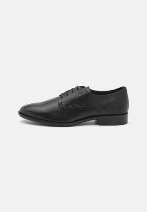 Schwarze Leder-Party-Schuhe mit strukturiertem Finish, spitzer Zehenform, Schnürverschluss und niedrigem Absatz. Keine sichtbaren Logos oder dekorativen Akzente.