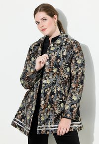 Mustikka-kuosiset takki mustassa kankaassa, jossa on monivärisiä kasviaiheitä, varustettuna kauluksella, napituslarilla ja koristeellisella reunan uurteella.