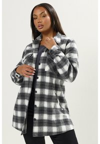 Mustavi musta-valkoinen ruudullinen flanellipaita, jossa on kauluskangas, napit edessä ja rintataskut. Pehmeä rakenne ja rento istuvuus.