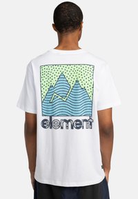 Camiseta blanca de algodón con un gráfico en la parte posterior que muestra montañas azules, líneas onduladas y un fondo verde con puntos. Logo "Element" en la parte inferior.