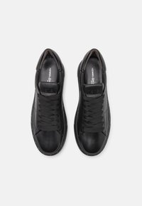 Paire de baskets en cuir noir à lacets avec semelle intérieure de marque, vues de dessus sur fond blanc.
