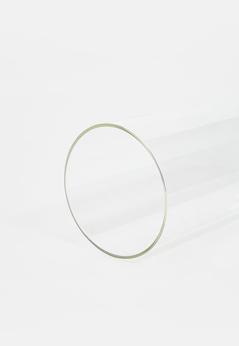 Przezroczysta szklana rurka, cylindryczny kształt, gładka powierzchnia, z cienką krawędzią na jednym końcu, odbijająca światło i rzucająca delikatne cienie.