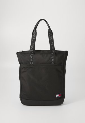 Black tote bag made of durable fabric, featuring a zippered top, two handles with “TOMMY JEANS” branding, and a front pocket.