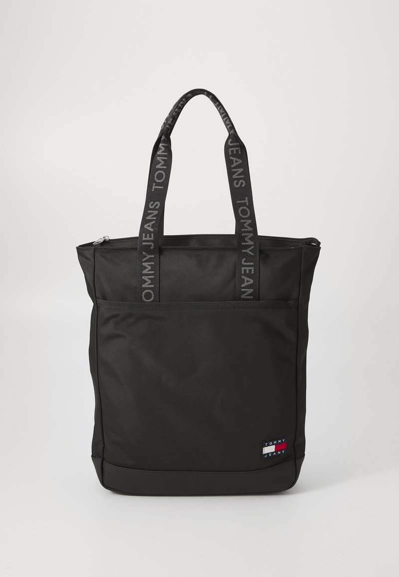 Svart toteväska i slitstark tyg med dragkedja upptill, två handtag med "TOMMY JEANS"-logotyp och en framficka.