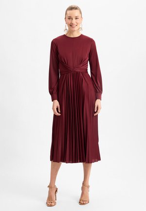 Burgunderfarbenes langärmeliges Kleid mit tailliertem Oberteil, plissiertem Rock und einer geknoteten Taillendetails. Glatter Stoff mit leichtem Glanz.