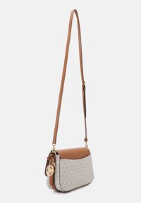 Beige and brown crossbody handbag with adjustable strap, monogram pattern, and gold-tone logo charm hanging on the side.