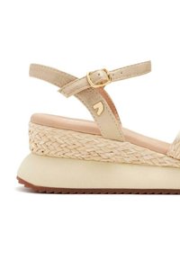 Sandalia de cuña beige con un tacón de yute tejido, hebilla en tono dorado y tiras texturizadas. Plantilla suave con suela de goma.
