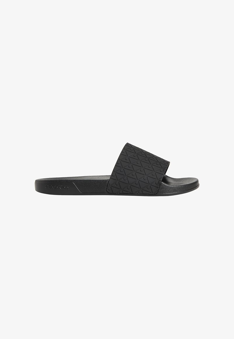 Sandale noire slip-on avec motif géométrique texturé sur une large bride et semelle rembourrée, vue de côté sur fond blanc.