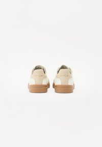 Sneakers bianchi con accenti beige, dotati di una tomaia in pelle liscia, forma rotonda e suola in gomma color cuoio. "REPLAY" è impresso sul tallone.
