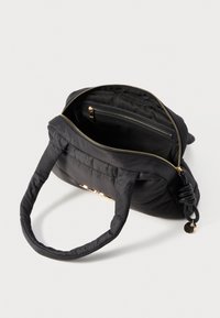 Bolsa de mão preta acolchoada com alças duplas, fecho dourado e bolso interior. Textura de tecido suave, formato compacto e design minimalista.