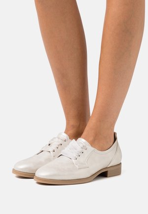 Weiße Lederschuhe mit texturierter Oberfläche, abgerundeter Spitze, Schnürung und niedrigem Blockabsatz.