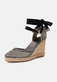 Wedge hak schoen met een grijze geweven stof bovenwerk met metallic accenten, zwarte lintstrikken rond de enkel en een touw omhulde platform.