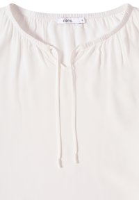Blusa bianca realizzata in tessuto leggero con scollatura a V, collo elastico e dettaglio con coulisse davanti. Etichetta con la scritta "CECIL."