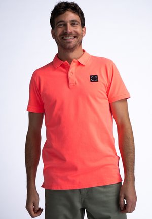 T-shirt polo néon orange vif avec col, trois boutons et un petit logo noir sur la poitrine gauche. Manches courtes et ourlet droit.