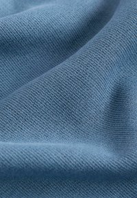 Tessuto blu lavorato a maglia con una superficie texture, caratterizzato da un motivo di tessitura uniforme e una caduta morbida. Il materiale appare leggero e liscio.