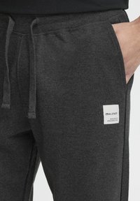 Grå fleece joggers med elastisk talje, snor og patch-label. Har en blød tekstur og sidelommer for praktisk brug.